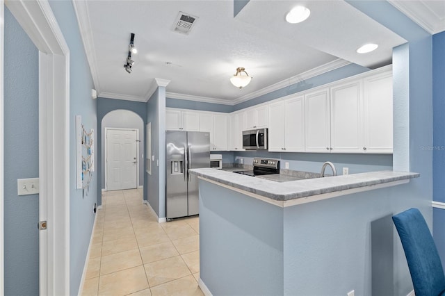 kitchen featuring a peninsula, appliances with stainless steel finishes, light tile patterned flooring, crown molding, and white cabinets