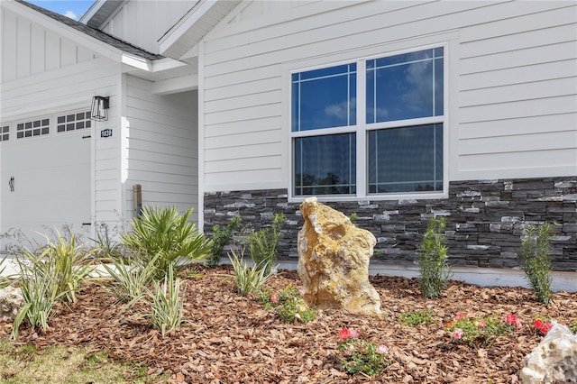 entrance to property featuring stone siding, board and batten siding, and an attached garage