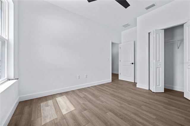 unfurnished bedroom with multiple windows, wood finished floors, and visible vents