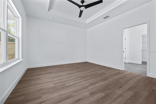 spare room featuring wood finished floors, visible vents, baseboards, ceiling fan, and a raised ceiling