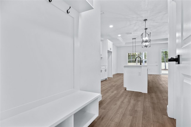 mudroom featuring a tray ceiling, recessed lighting, wood finished floors, a notable chandelier, and a sink