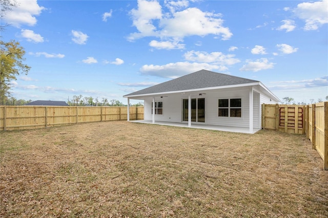 back of property with a fenced backyard, a lawn, a patio, and roof with shingles