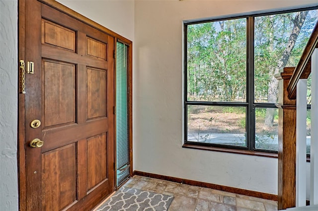 entryway with stone tile floors, a wealth of natural light, and baseboards