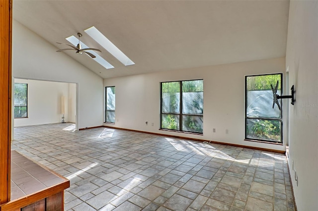 empty room with a skylight, baseboards, and high vaulted ceiling