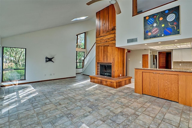 unfurnished living room with visible vents, baseboards, high vaulted ceiling, and a healthy amount of sunlight