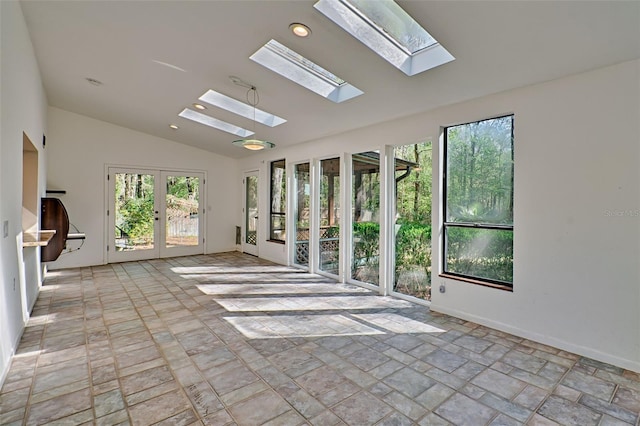 empty room featuring lofted ceiling with skylight, recessed lighting, stone finish flooring, and baseboards