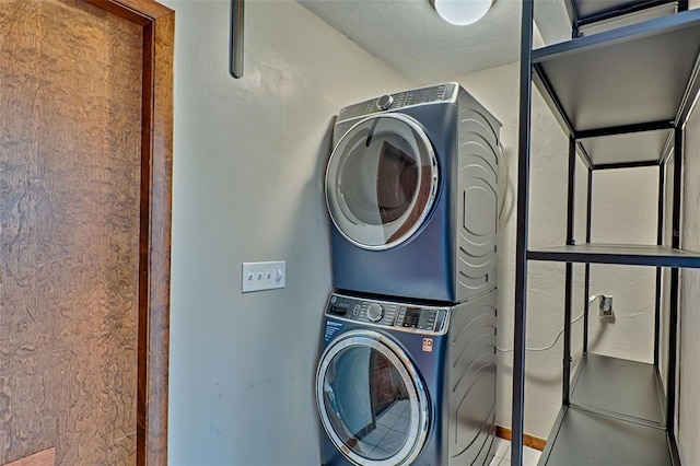 clothes washing area featuring stacked washer and clothes dryer and laundry area