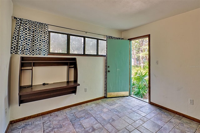 empty room with baseboards and stone tile floors