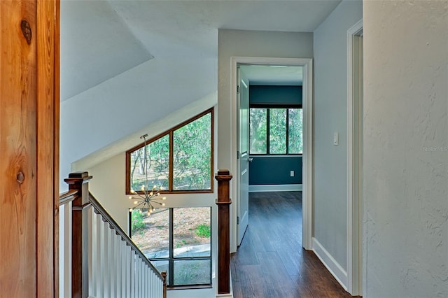 interior space with an upstairs landing, dark wood finished floors, baseboards, and a textured wall