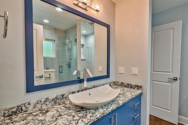 full bathroom with vanity, a shower stall, recessed lighting, and a textured wall