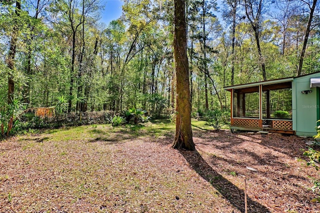 view of yard with a forest view and a sunroom