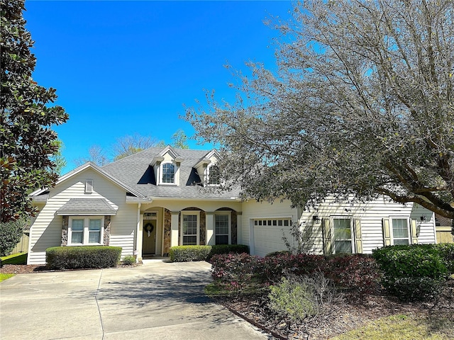 cape cod-style house featuring an attached garage, driveway, and a shingled roof