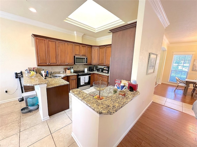 kitchen with a breakfast bar area, a peninsula, ornamental molding, stainless steel appliances, and brown cabinets