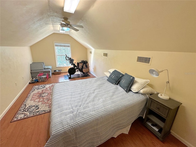 bedroom with visible vents, baseboards, wood finished floors, and vaulted ceiling