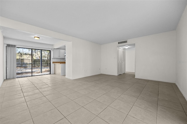 empty room with light tile patterned floors, baseboards, and visible vents