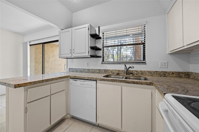 kitchen featuring light tile patterned floors, a peninsula, white dishwasher, white cabinets, and a sink