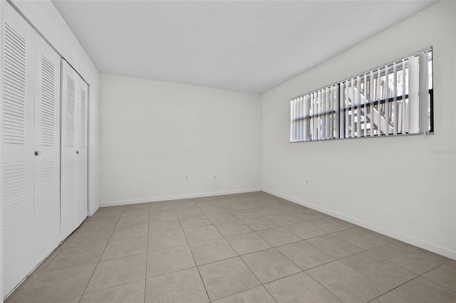 unfurnished bedroom with a closet, a textured ceiling, and baseboards