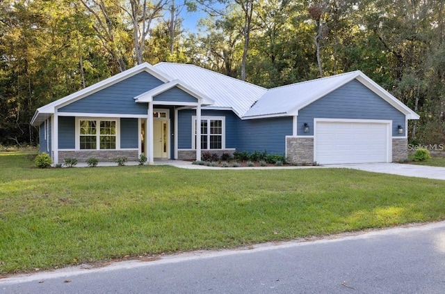 view of front of home featuring stone siding, metal roof, concrete driveway, a front yard, and a garage