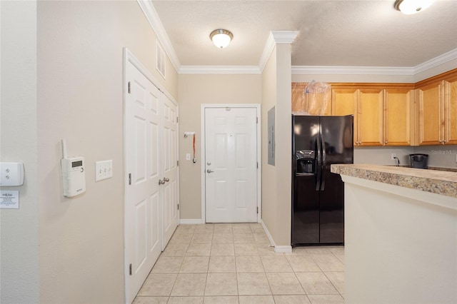 kitchen with visible vents, crown molding, light countertops, light tile patterned floors, and black fridge