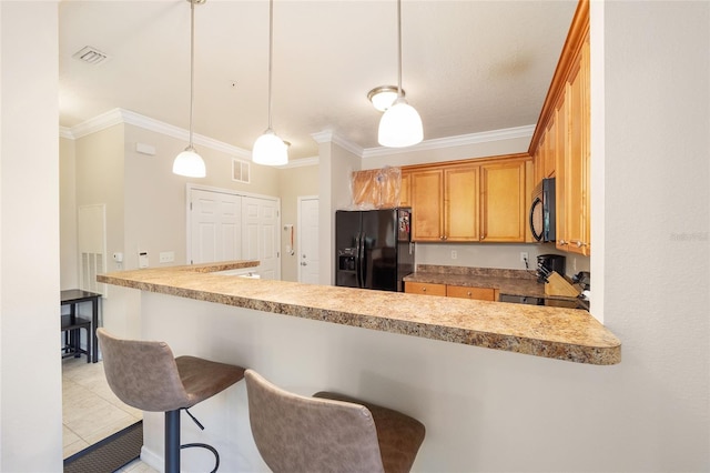 kitchen featuring a breakfast bar, black appliances, crown molding, and visible vents