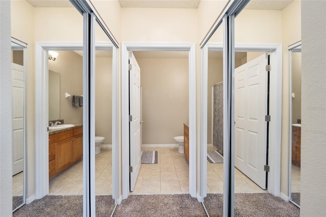 hall with a sink, light colored carpet, and light tile patterned floors