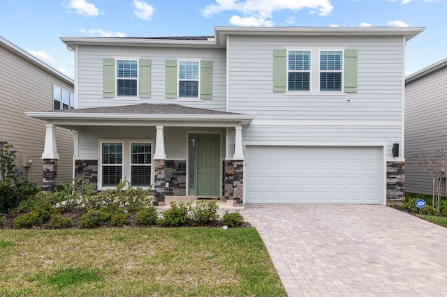 view of front of home featuring a porch, decorative driveway, a garage, and stone siding