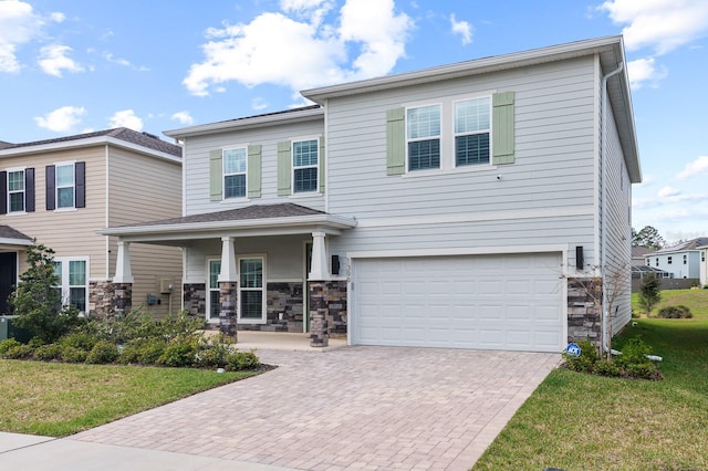 view of front of property featuring stone siding, an attached garage, decorative driveway, and a front yard