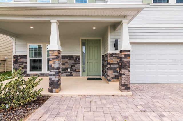 entrance to property featuring a garage and stone siding