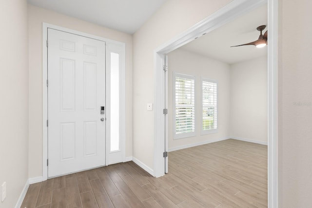 foyer entrance with ceiling fan, baseboards, and wood finished floors