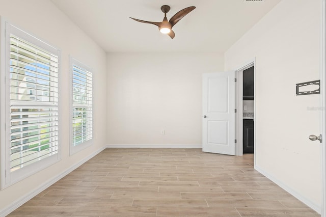 empty room featuring visible vents, baseboards, light wood-style floors, and ceiling fan