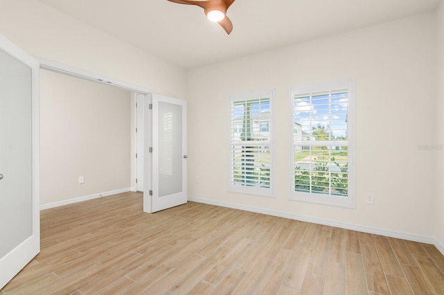 empty room with light wood-style floors, baseboards, and ceiling fan