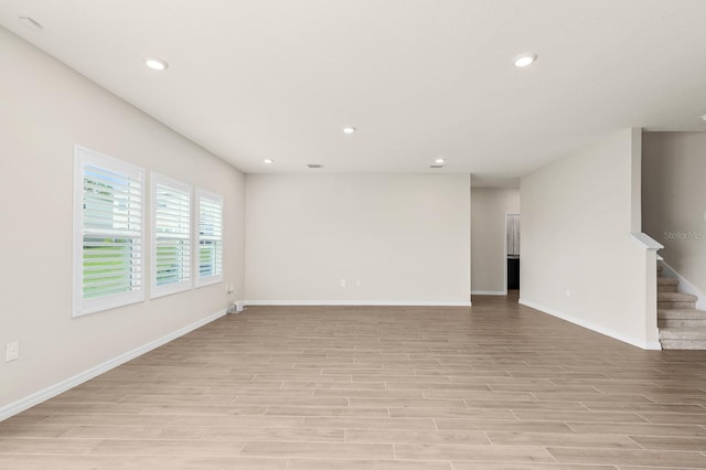 unfurnished living room with stairs, recessed lighting, baseboards, and light wood finished floors