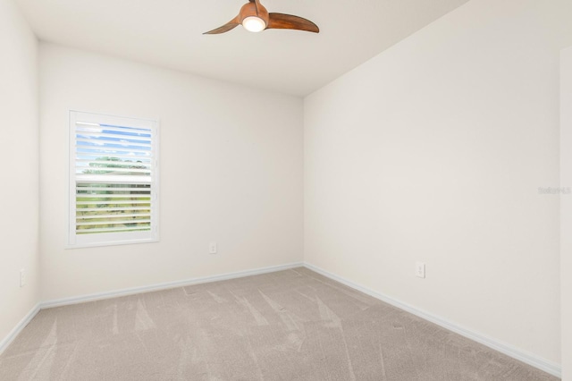 unfurnished room featuring baseboards, light carpet, and a ceiling fan