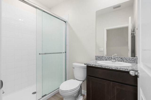 bathroom with vanity, a shower stall, toilet, and visible vents