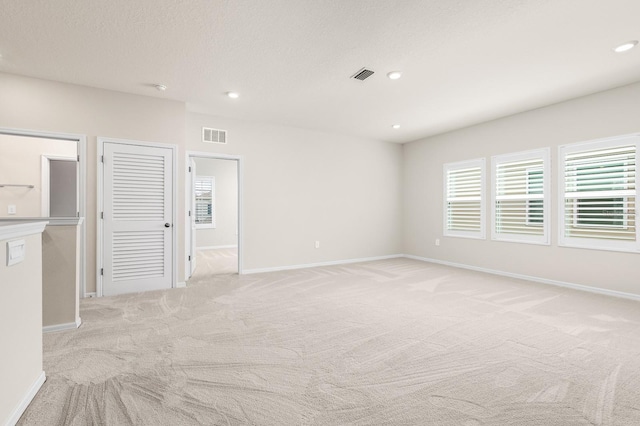 spare room featuring recessed lighting, visible vents, light carpet, and baseboards