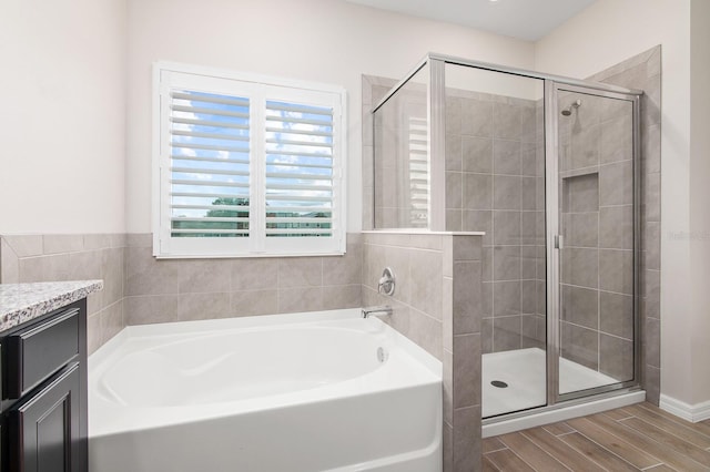 full bathroom featuring wood tiled floor, vanity, a garden tub, and a shower stall