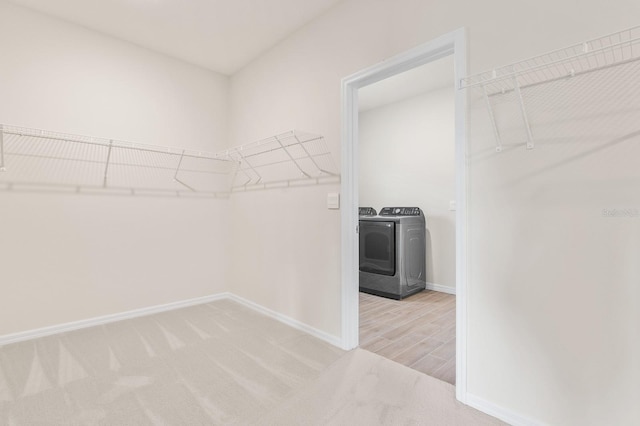 spacious closet with light carpet, washer and dryer, and a wood stove