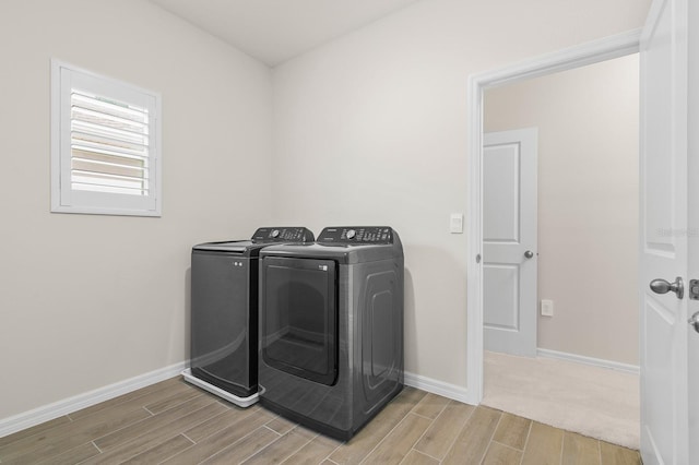 clothes washing area with wood finish floors, baseboards, washing machine and dryer, and laundry area