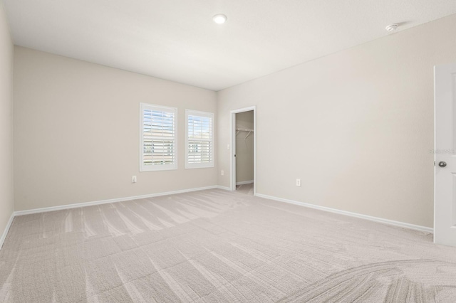 unfurnished room featuring light colored carpet and baseboards