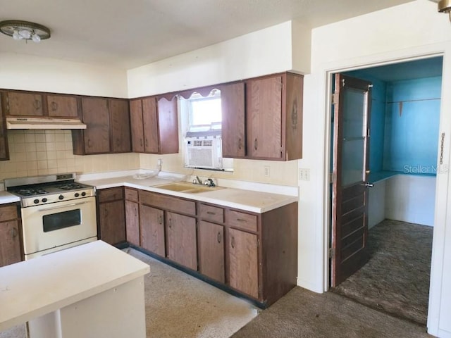 kitchen with under cabinet range hood, a sink, backsplash, white gas range oven, and light countertops