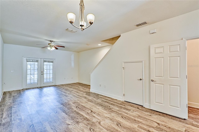 unfurnished living room with light wood-style flooring, ceiling fan with notable chandelier, visible vents, and french doors