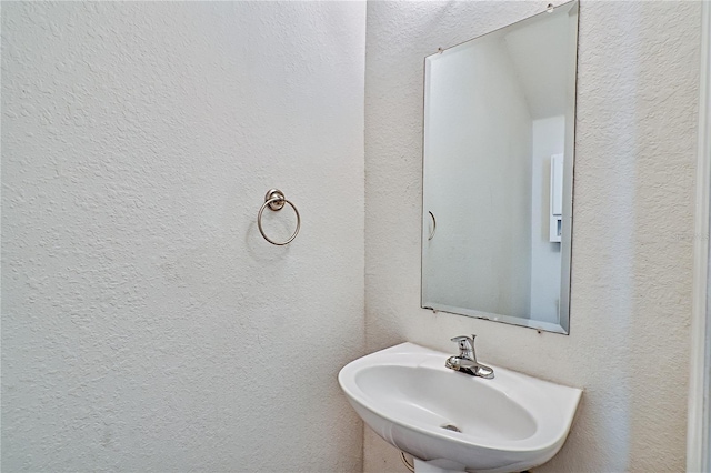 bathroom featuring a textured wall and a sink