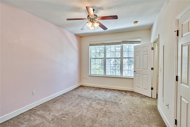 carpeted empty room with ceiling fan, a textured ceiling, and baseboards