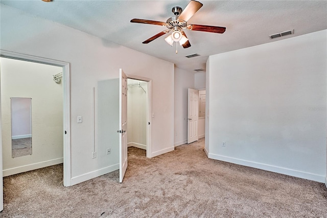 unfurnished bedroom featuring visible vents, carpet floors, and a walk in closet