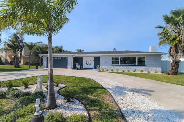 ranch-style house with concrete driveway, a front yard, a garage, and stone siding