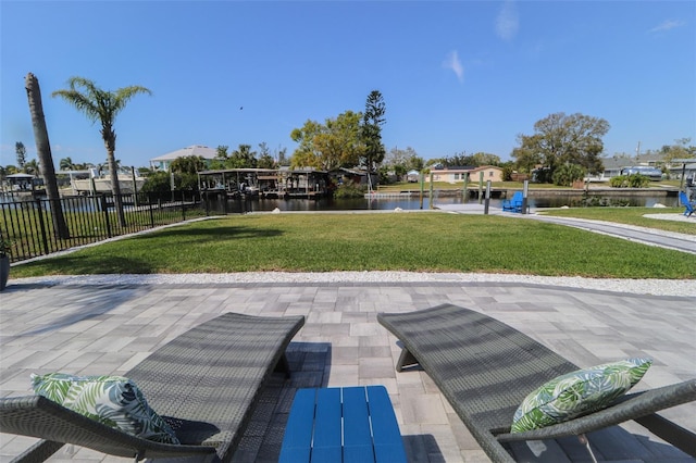 view of community featuring a patio, a yard, fence, and a water view