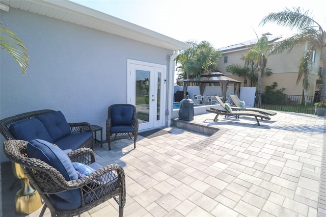 view of patio with a gazebo, an outdoor living space, french doors, and fence