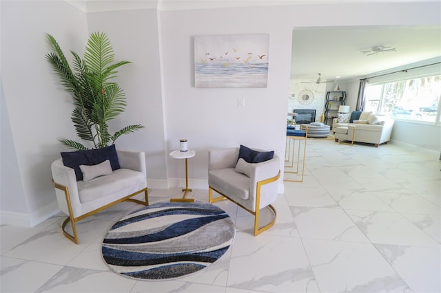 sitting room featuring baseboards, a large fireplace, and marble finish floor