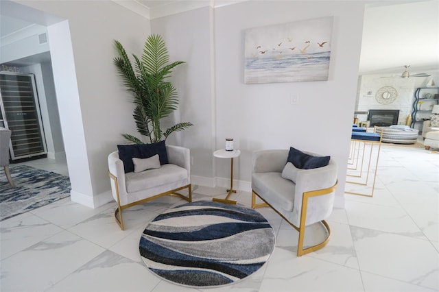 sitting room featuring baseboards, ceiling fan, ornamental molding, a fireplace, and marble finish floor