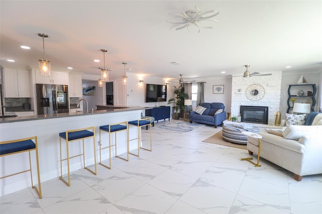 living room with marble finish floor, ornamental molding, a ceiling fan, recessed lighting, and a fireplace